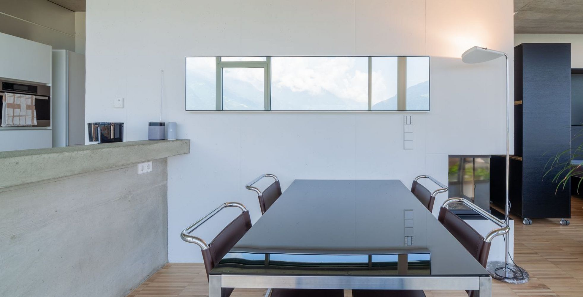 Moderner Essbereich mit schwarzem Glastisch, braunen Stühlen, Stehlampe und Topfpflanze Moderner Essbereich mit schwarzem Glastisch, braunen Stühlen, Stehlampe und Topfpflanze