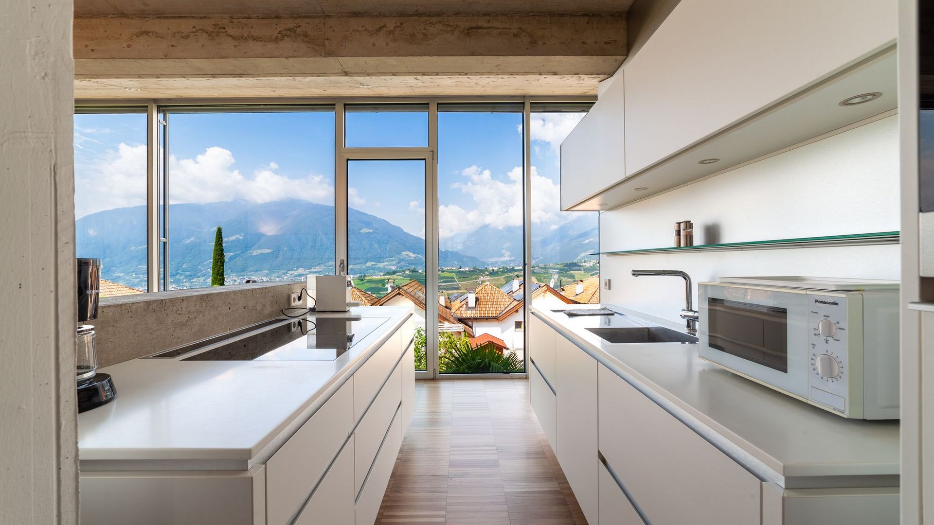 Helle, moderne Weißküche mit großer Fensterfront und Blick auf Berge und rote Dachziegel Helle, moderne Weißküche mit großer Fensterfront und Blick auf Berge und rote Dachziegel