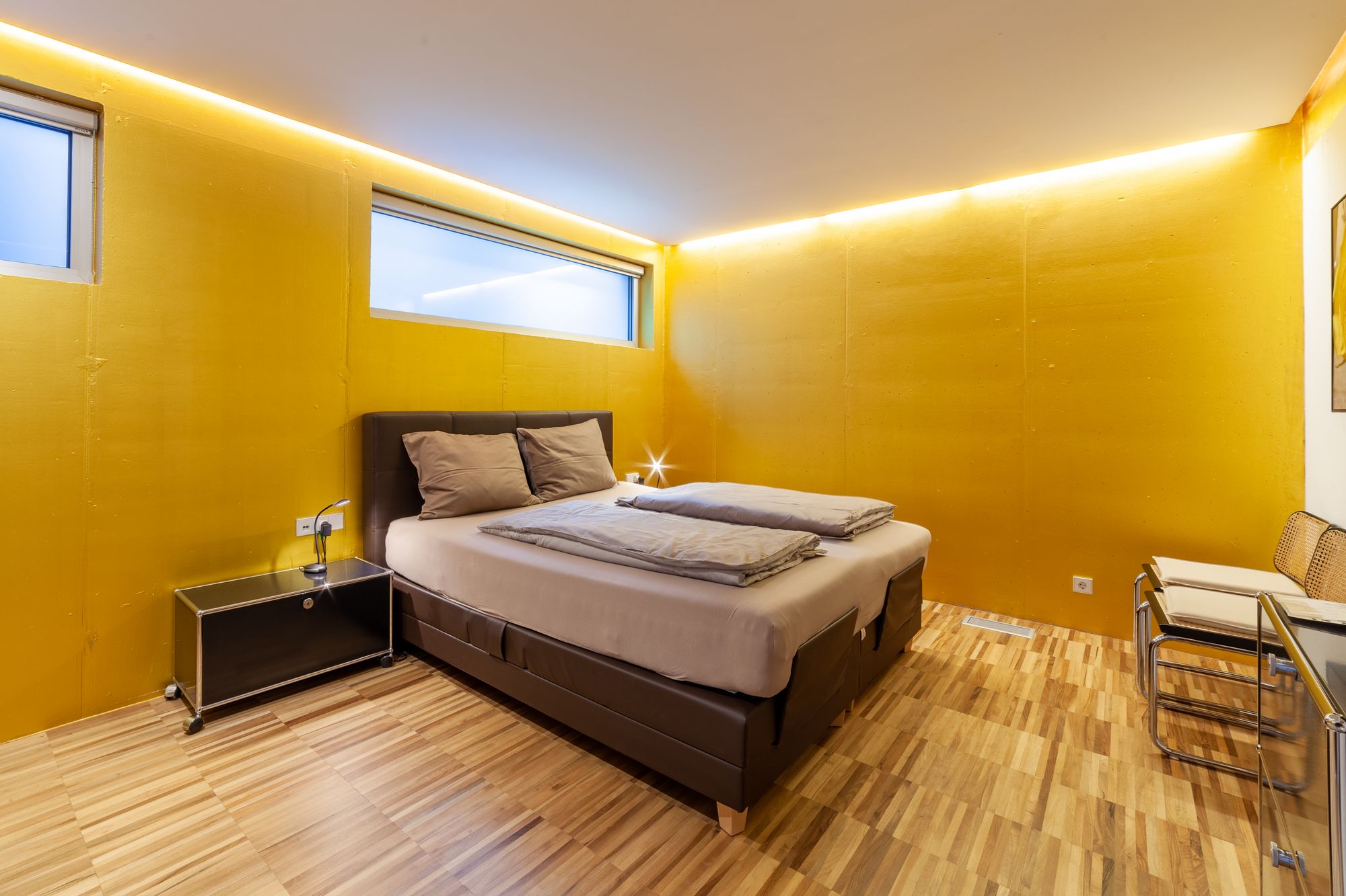 Modernes Schlafzimmer mit gelben Wänden, Doppelbett und Holzfußboden. Modernes Schlafzimmer mit gelben Wänden, Doppelbett und Holzfußboden.